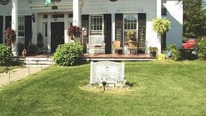 A two-story white building with a front porch, a flag, and a well-maintained lawn.