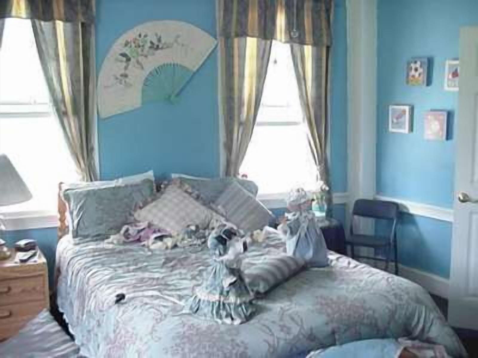 A bedroom with a bed, a dresser, and a window with curtains.