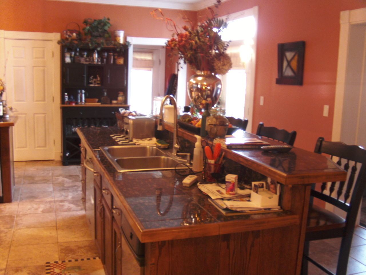 Una cocina con una isla central, una mesa de comedor con sillas y una puerta que da a otra habitación.