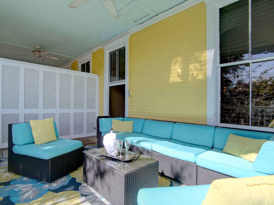 Une pièce lumineuse, aux couleurs bleu et jaune, comprenant un canapé d’angle, une table basse et une statue d’oiseau décorative.