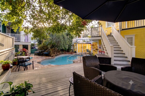 A wooden deck with outdoor furniture, a swimming pool, and a staircase leading to a second floor. - Azalea Inn and Villas (Savannah)