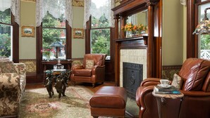 A traditional living room with leather sofas, a fireplace, and a large window with lace curtains.