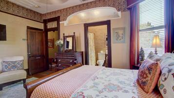 A bedroom with a bed, dresser, and a bathroom visible through an archway.