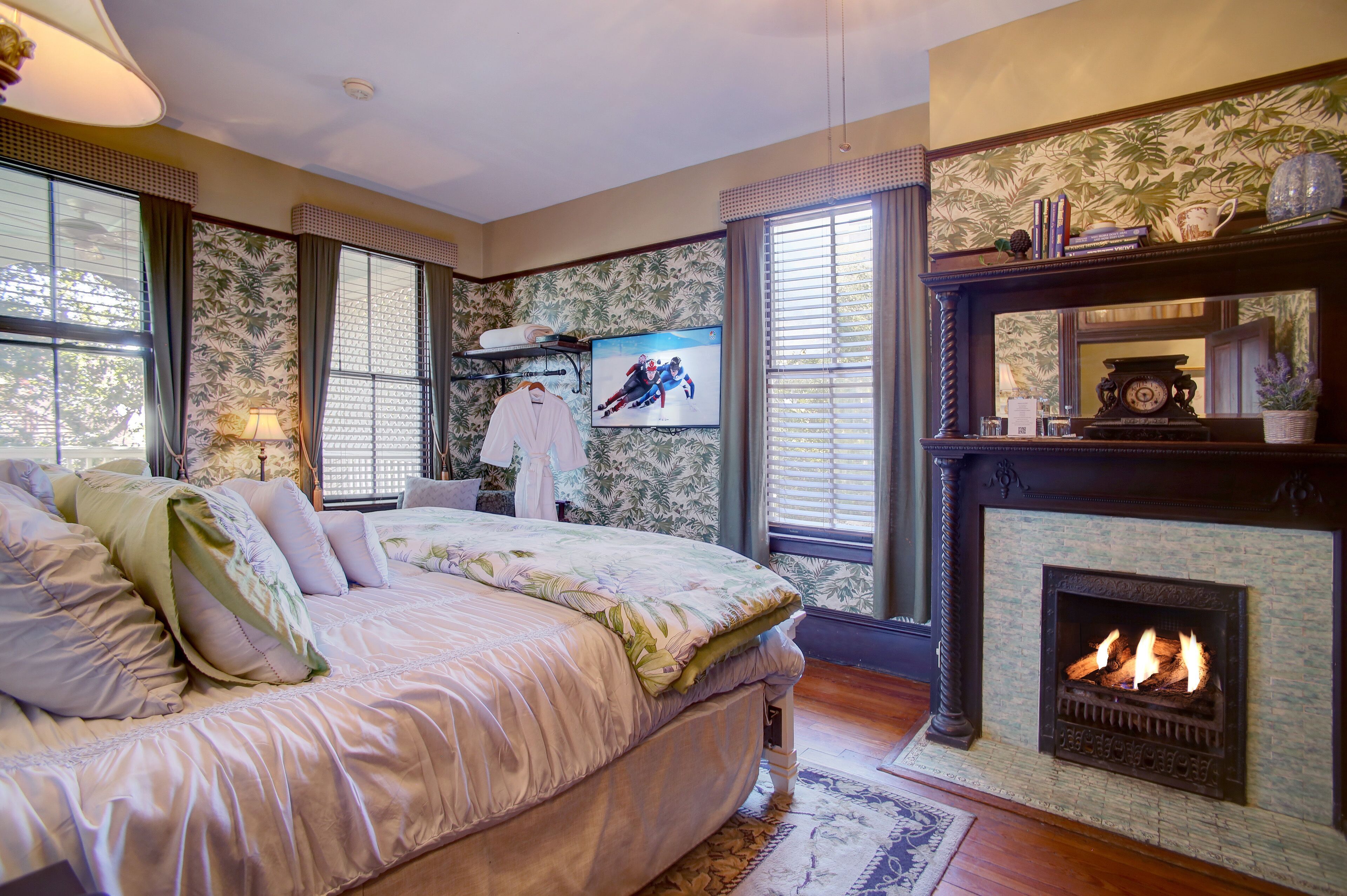 Een slaapkamer met een groot bed, een open haard en een televisie aan de muur.