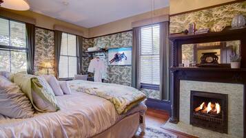 Een slaapkamer met een groot bed, een open haard en een televisie aan de muur.