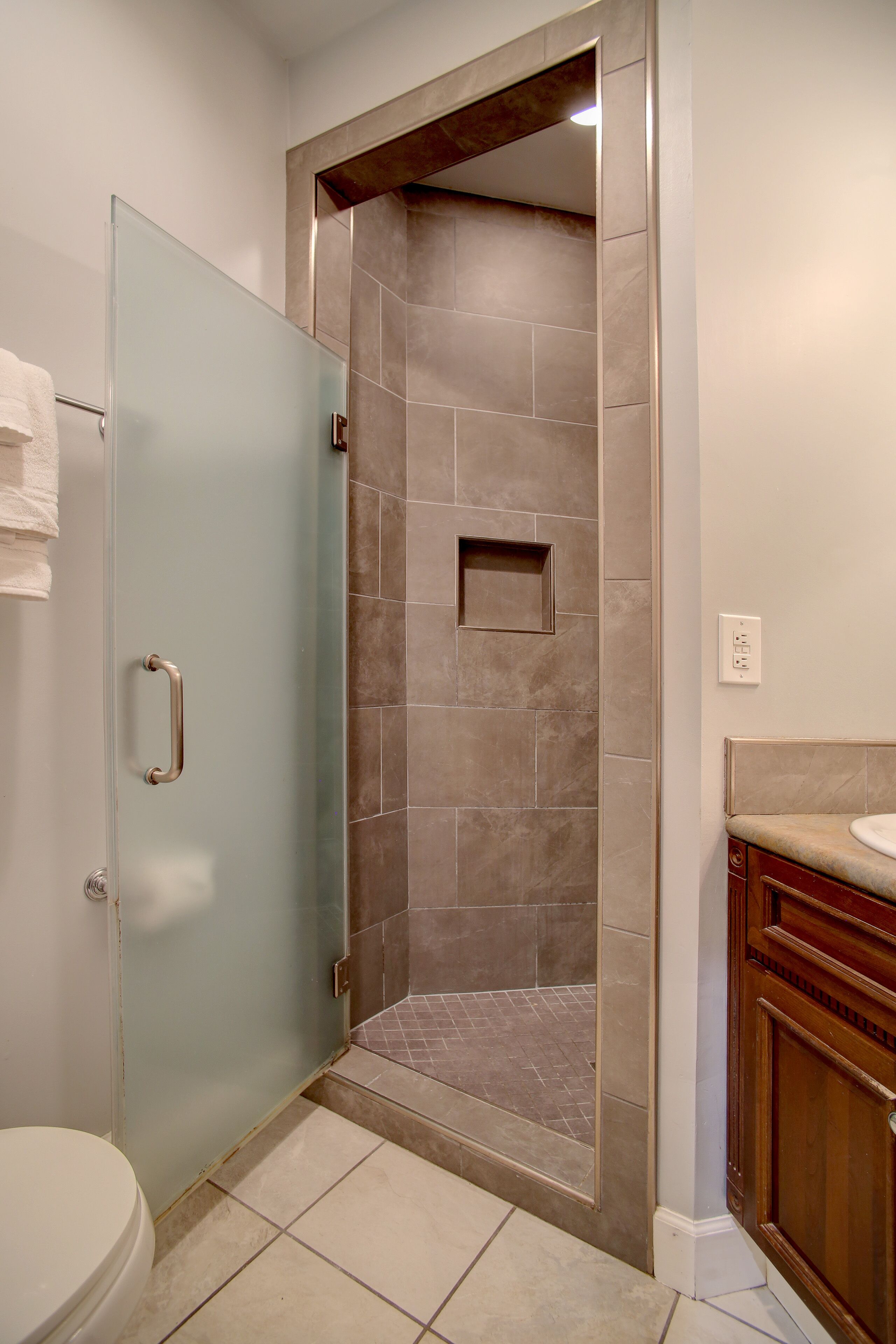 Une salle de bain avec une porte de douche en verre, des toilettes et un meuble-lavabo avec un évier.
