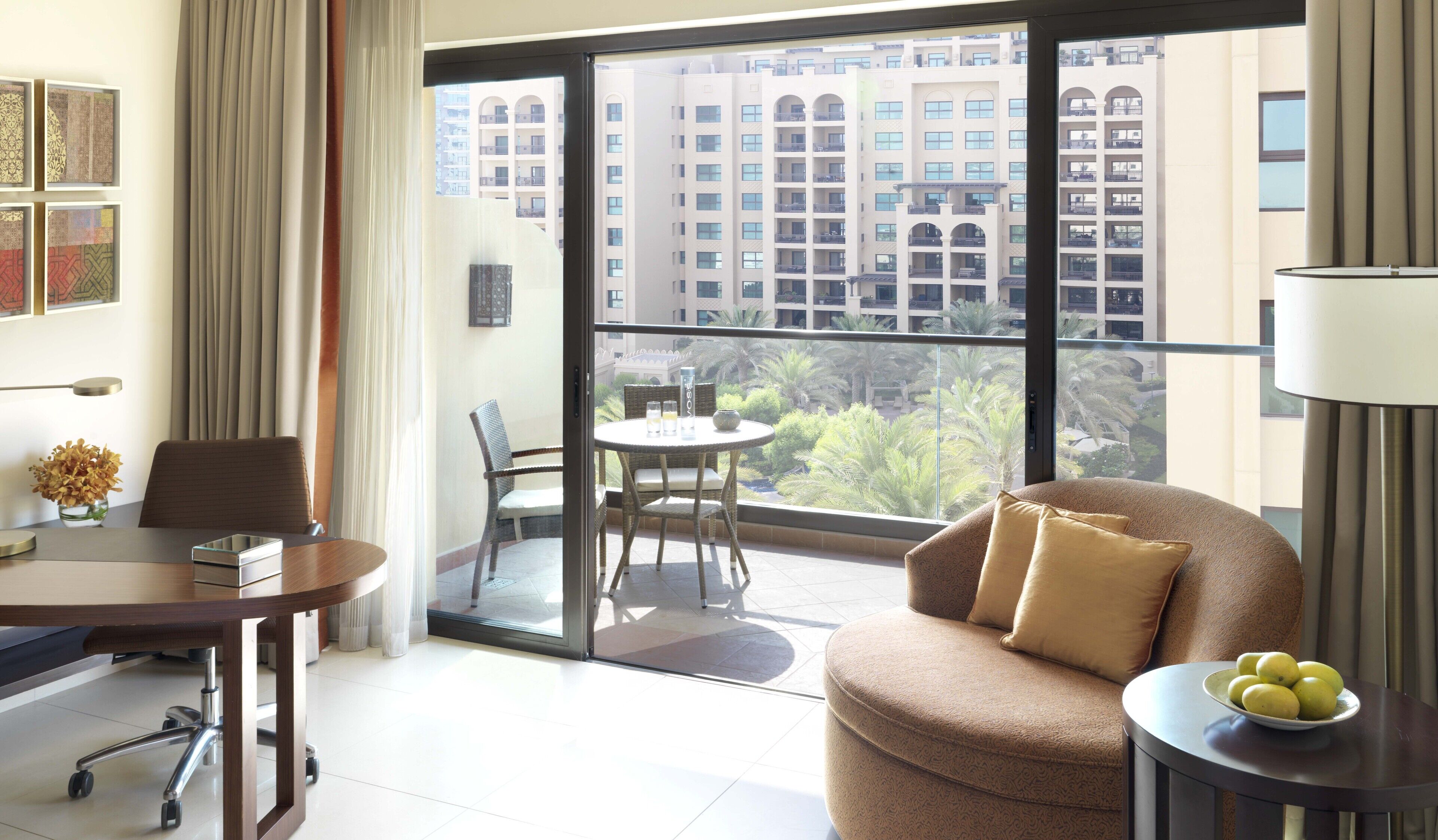 Ein modernes Hotelzimmer mit Balkon, Essbereich und Blick auf ein Hochhaus.