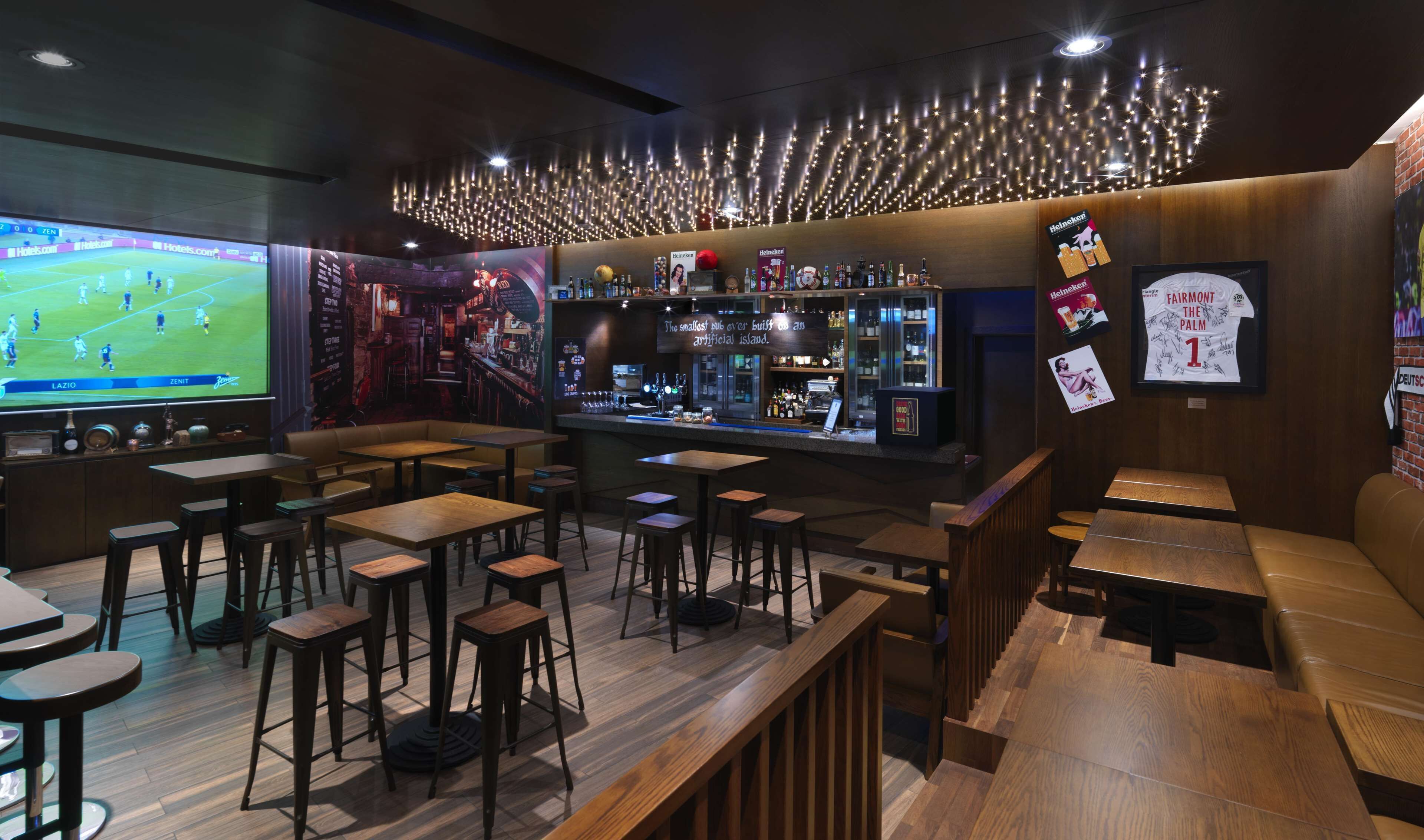 Eine Bar mit Holzkubaturen, einem Fernseher, der ein Fußballspiel zeigt, und verschiedenen Heineken-Werbeanzeigen.