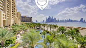 A resort with a pool, palm trees, and a city skyline in the background.