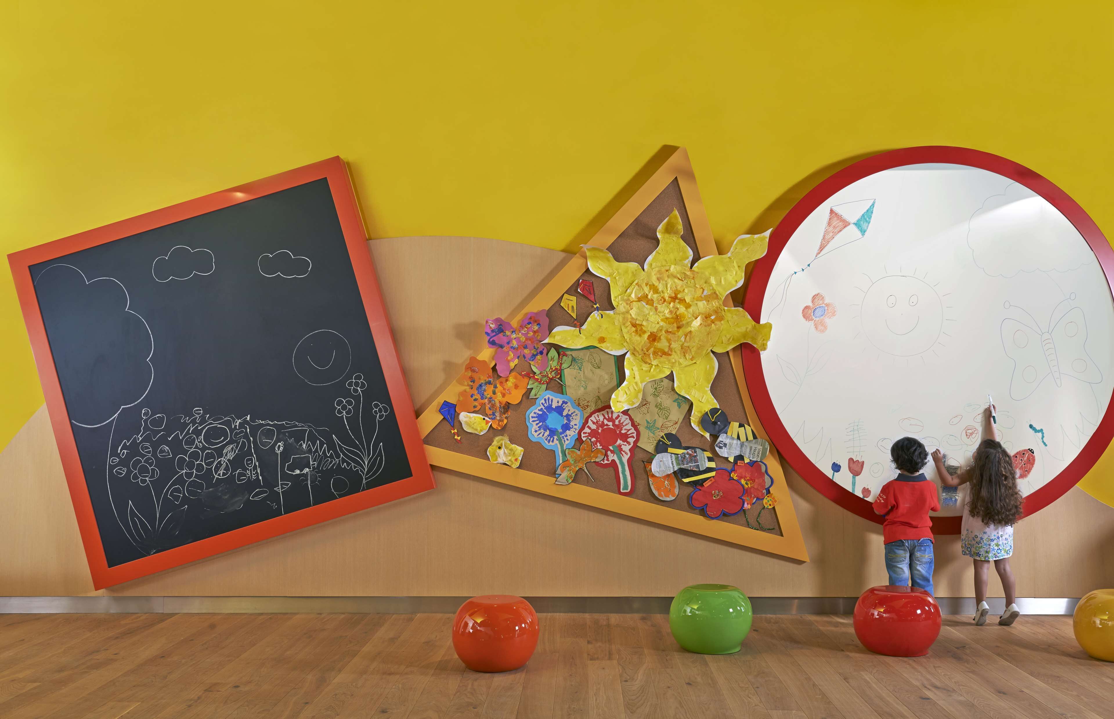 A room with a large chalkboard, a colorful artwork, and a round mirror.