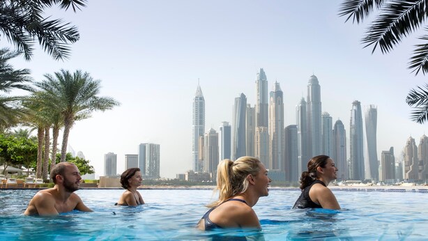 A swimming pool with a cityscape view, including tall buildings and palm trees.