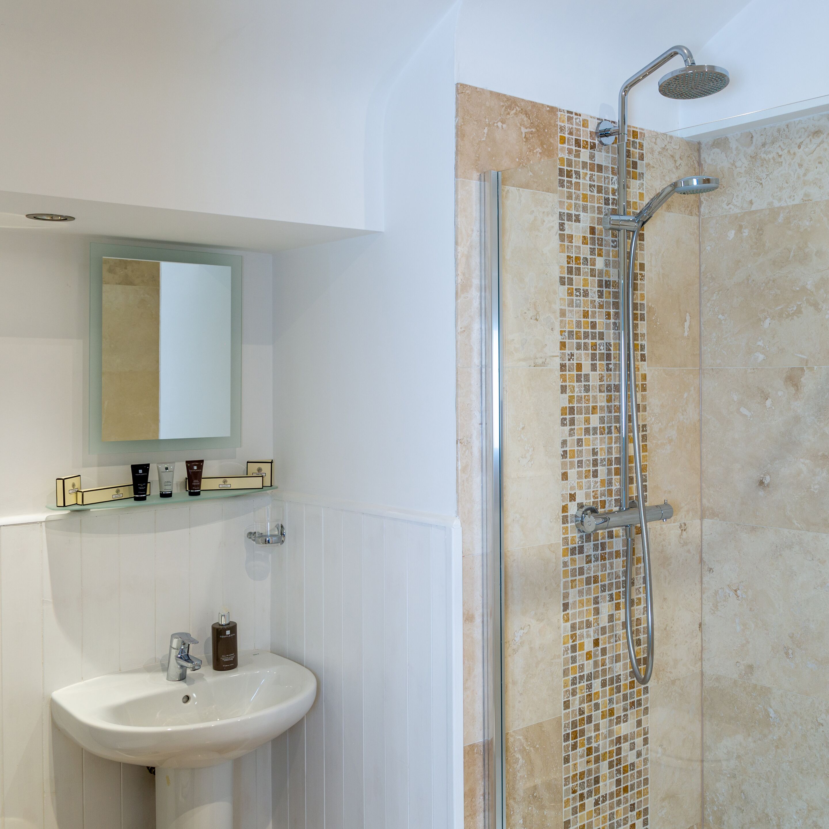 A bathroom with a shower, a sink, and a mirror.