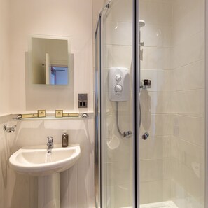 A modern bathroom with a glass shower enclosure, a white sink, and a mirror above the sink. - The Craven Heifer Addingham (Ilkley)