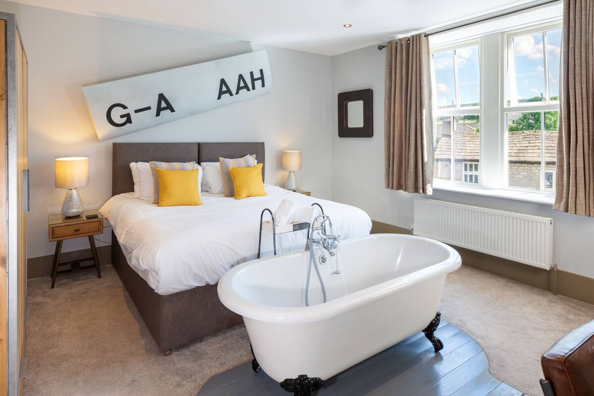A bedroom with a large bed, a bathtub, and a window with curtains.