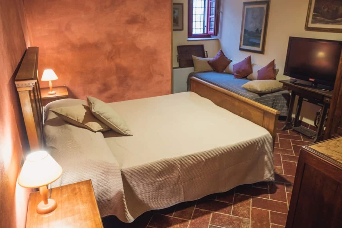 A bedroom with a bed, bedside lamps, a television, and a window.