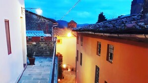 A narrow alleyway with stone pavement, flanked by buildings with small windows and a warm glow from lights. - San Gennaro Castello (Capannori)