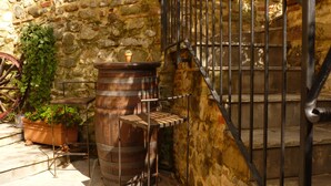 A rustic stone wall, a wooden barrel, a metal chair, and a metal staircase with a railing. - San Gennaro Castello (Capannori)