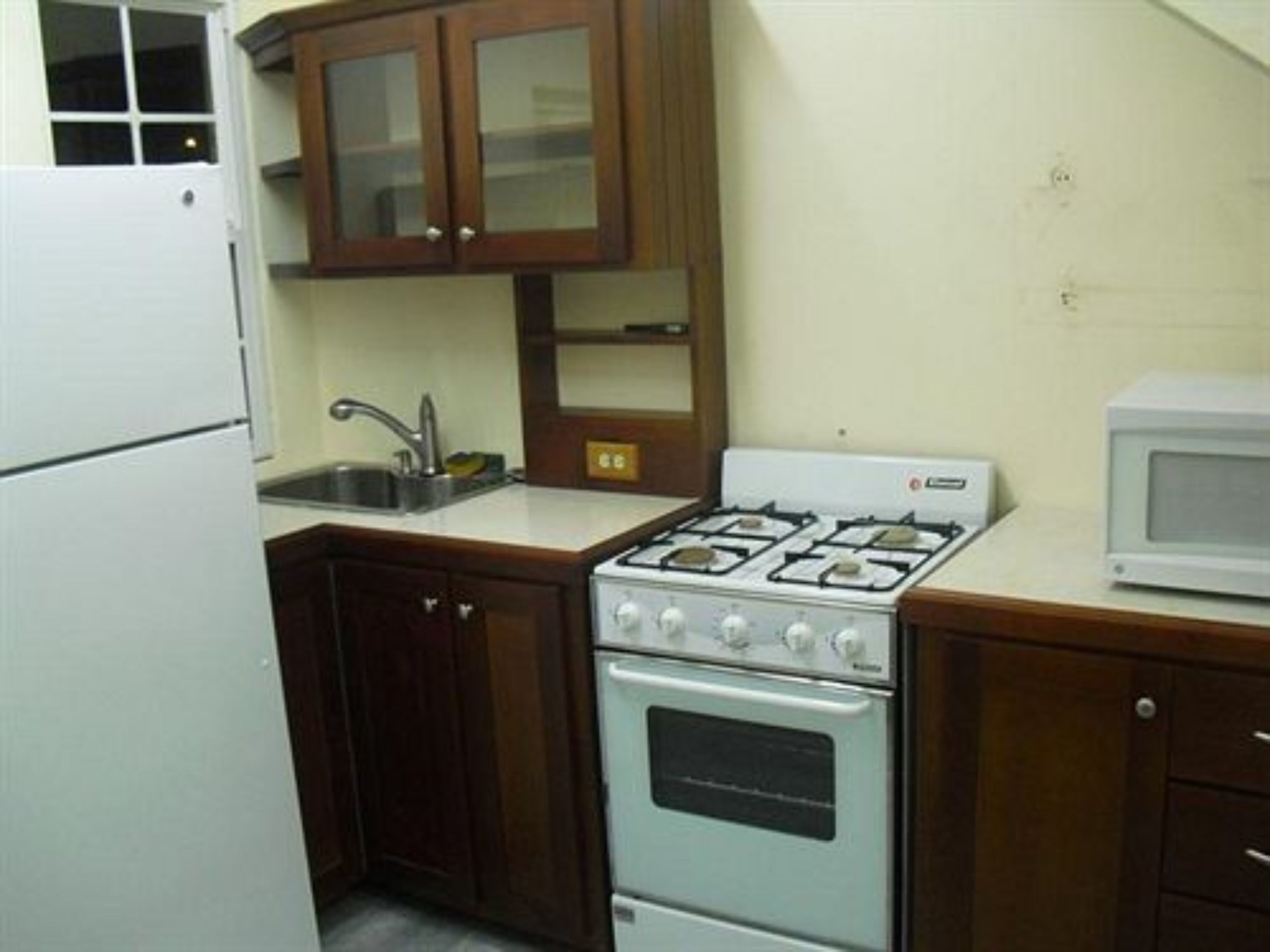 A compact kitchen with a white stove, a microwave, and wooden cabinets.