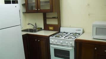 A compact kitchen with a white stove, a microwave, and wooden cabinets.