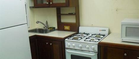 Una cocina compacta con estufa blanca, microondas y muebles de madera.