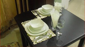 A dining table set with plates, cutlery, and a glass. - Piarco Village Suites (Piarco)
