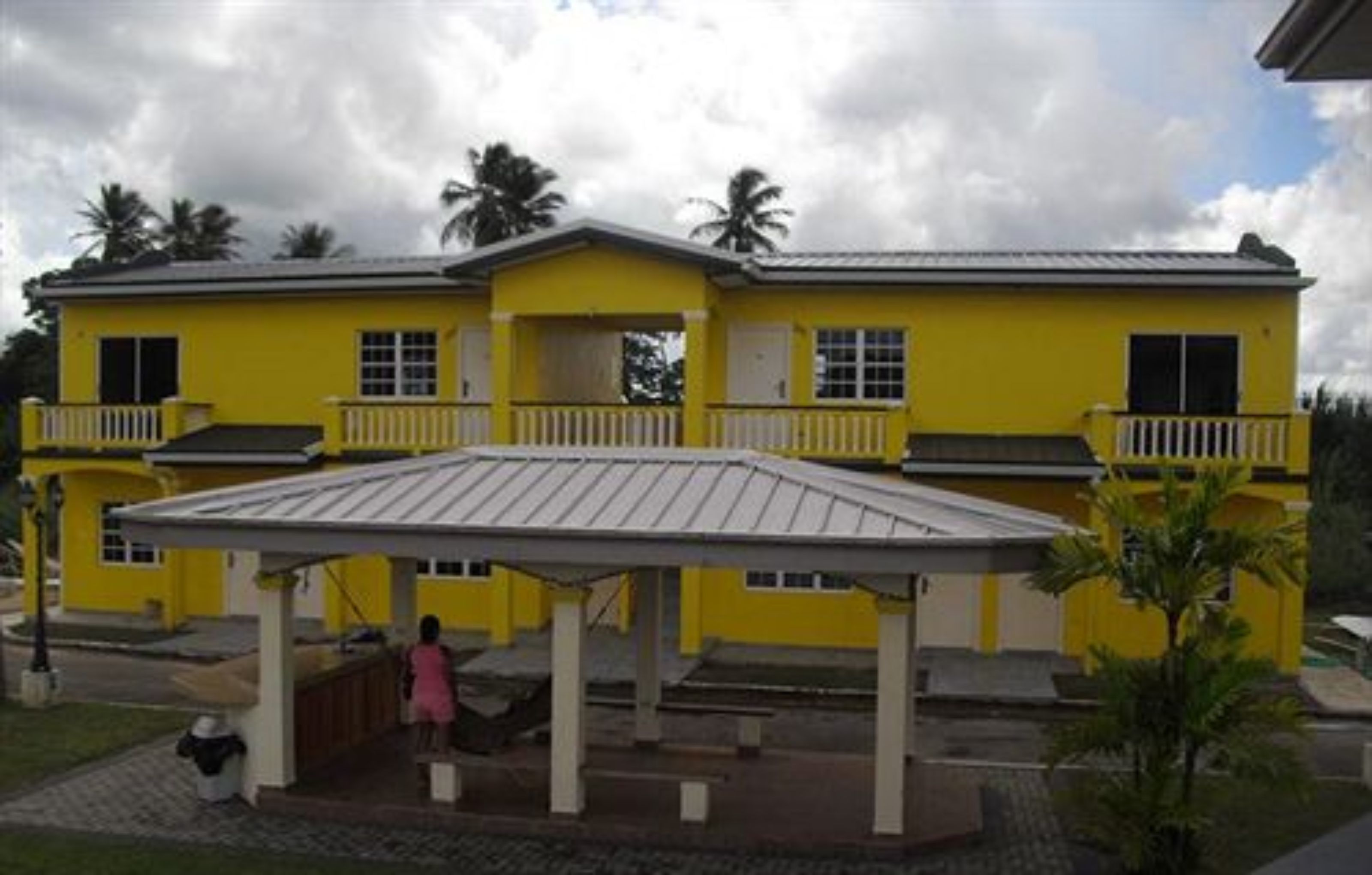 Un edificio giallo con un portico coperto e un piccolo balcone.