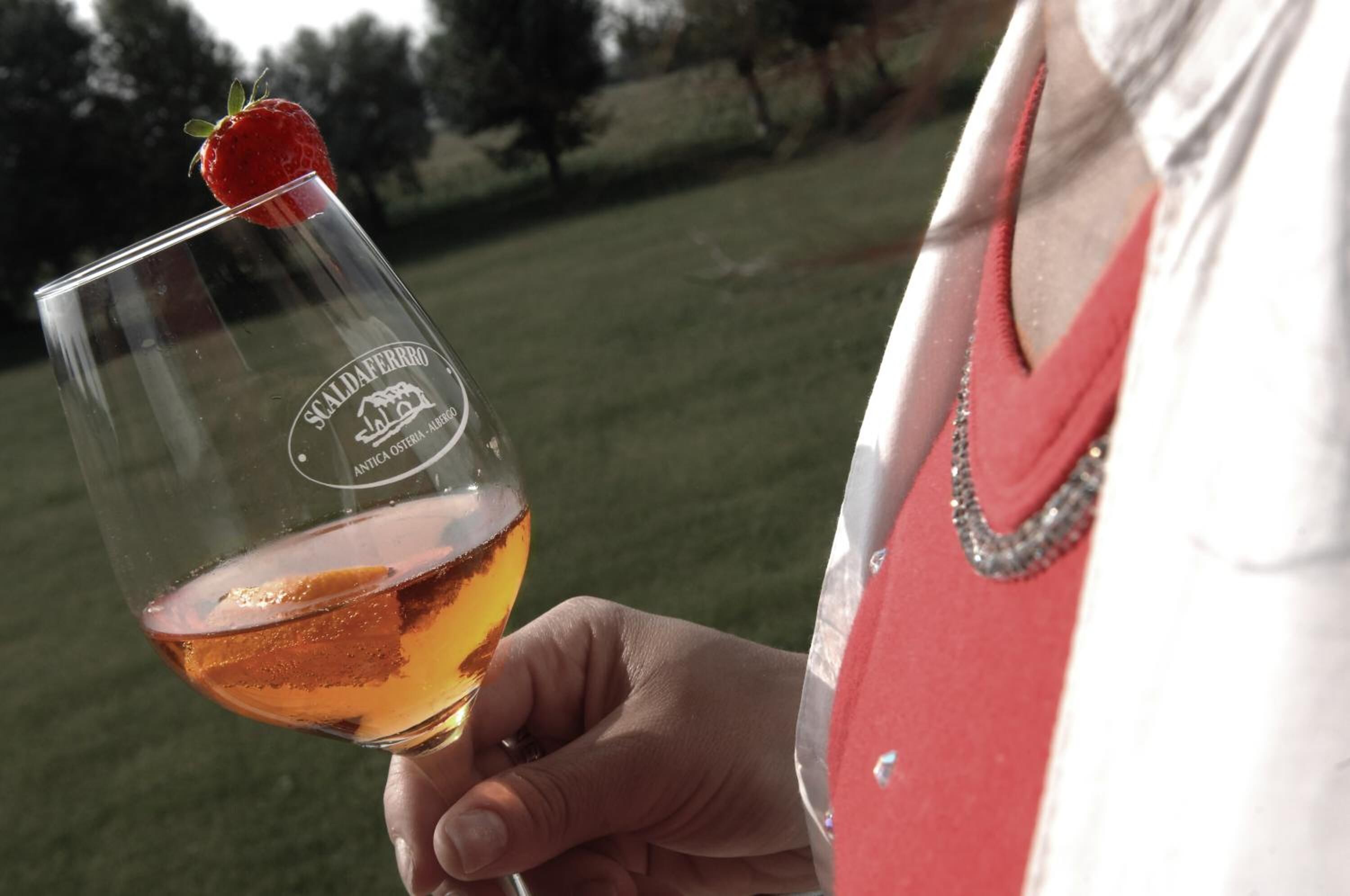 A person holding a glass with a strawberry on top, and the glass has a logo that reads "Scalaferrero".