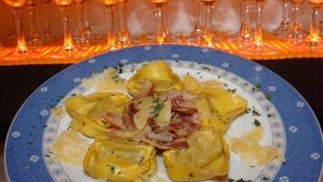 A plate of ravioli with a garnish of onions and herbs, served on a blue and white floral plate.