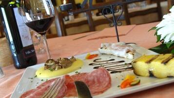 A dining table with a plate of food, a bottle of wine, and a candle.