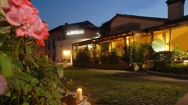 A building with the name "ALBERGO" illuminated at night, surrounded by greenery and a cobblestone path. - Albergo Scaldaferro (Sandrigo)