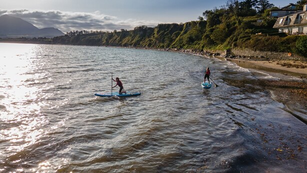 A beach with two paddleboarders. - Woodside Lodge (Westport)