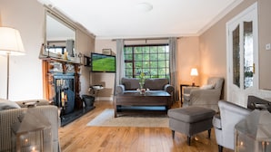 A cozy living room with a fireplace, comfortable seating, and a television. - Woodside Lodge (Westport)