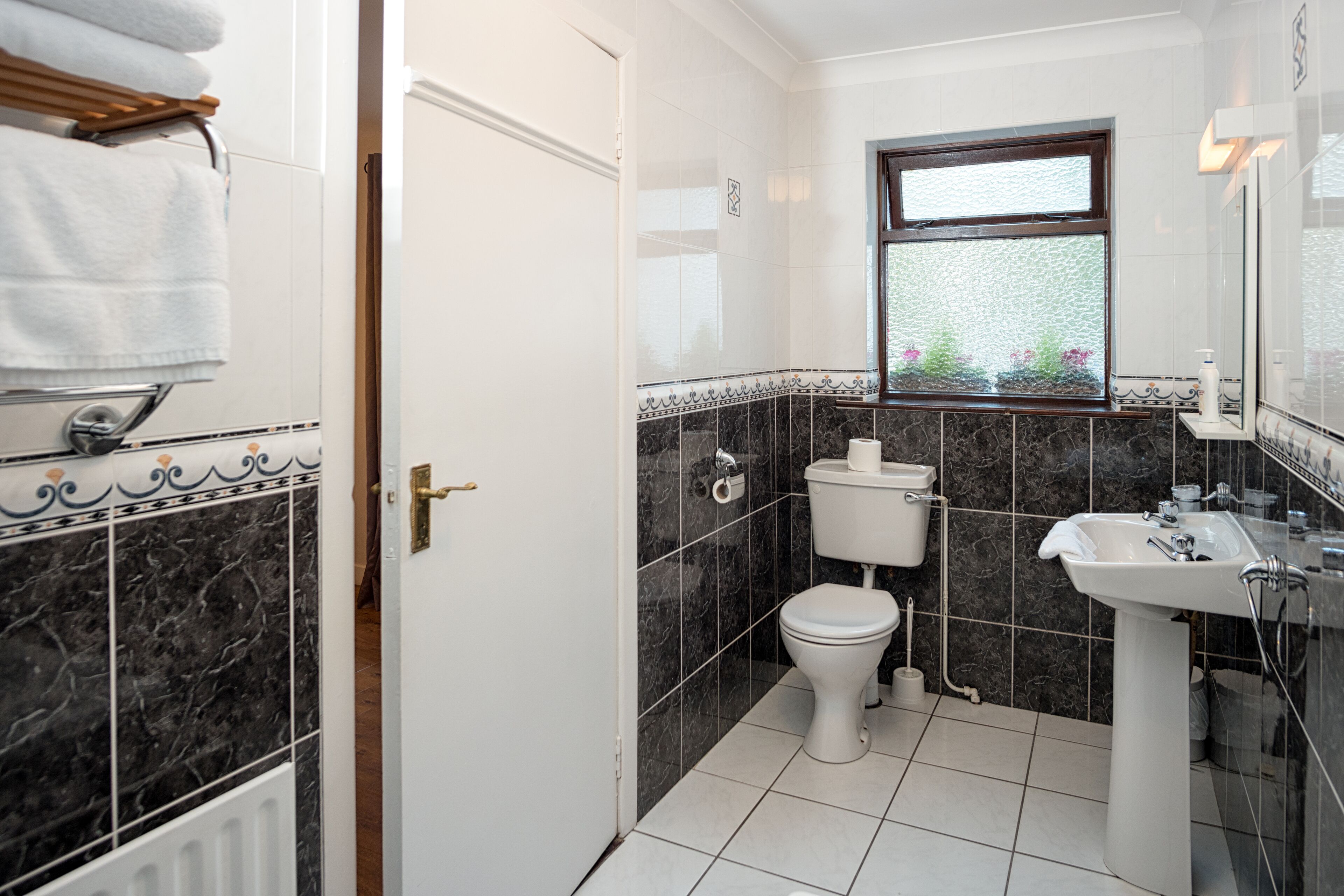 Et badeværelse med toilet, håndvask og vindue.