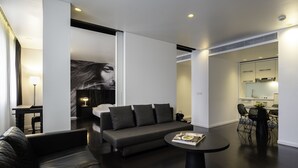 A modern living room with a sofa, a coffee table, and a dining area with chairs and a table. - B-aparthotel Regent (Brussels)