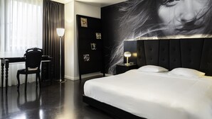 A modern hotel room with a large bed, a desk, and a chair. - B-aparthotel Regent (Brussels)