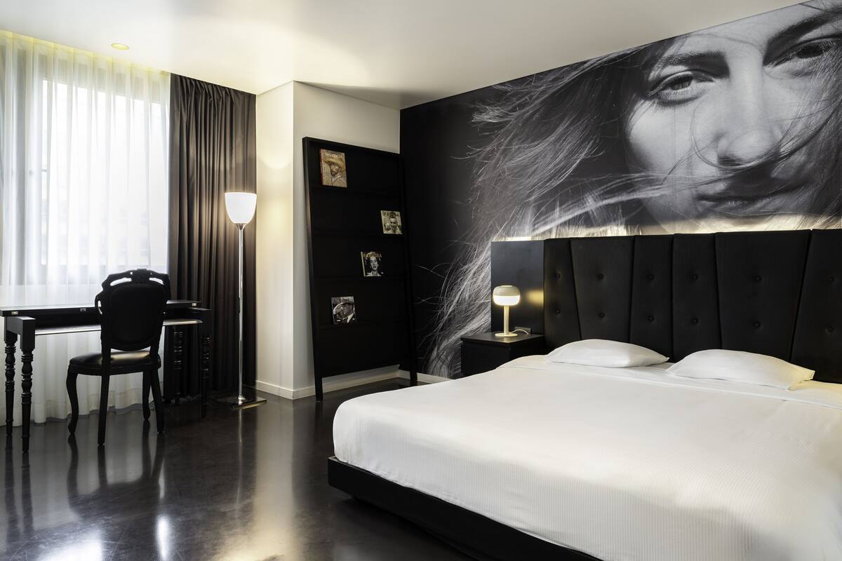 Una habitación de hotel moderna con una cama grande, un escritorio y una silla.