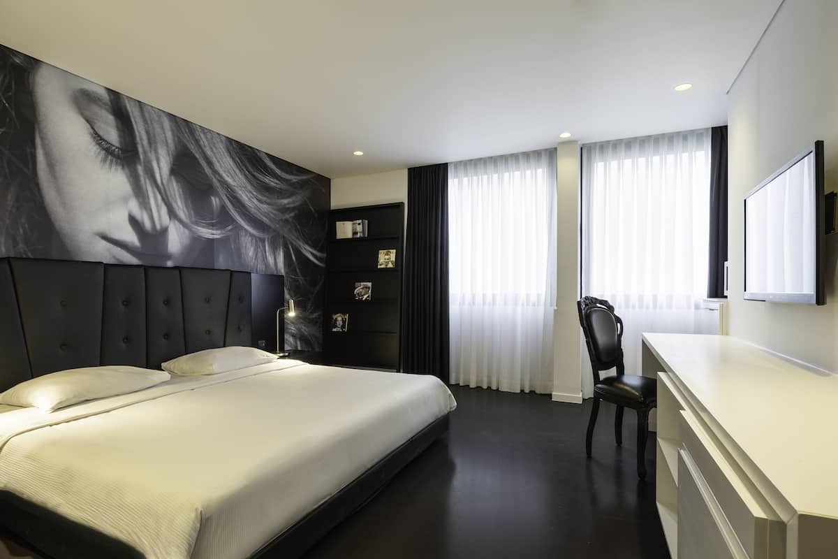 Una habitación de hotel moderna con una cama grande, un escritorio y una silla.