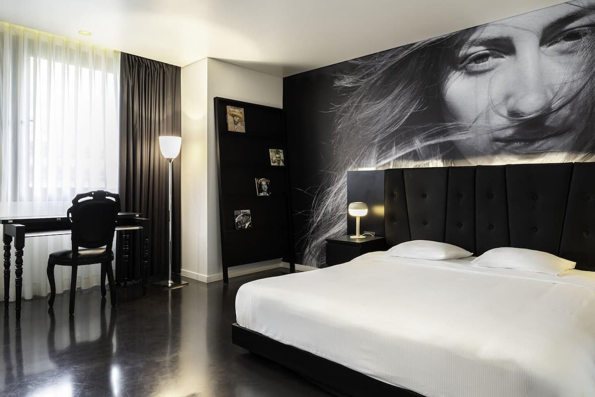 Una habitación de hotel moderna con una cama grande, un escritorio y una silla.