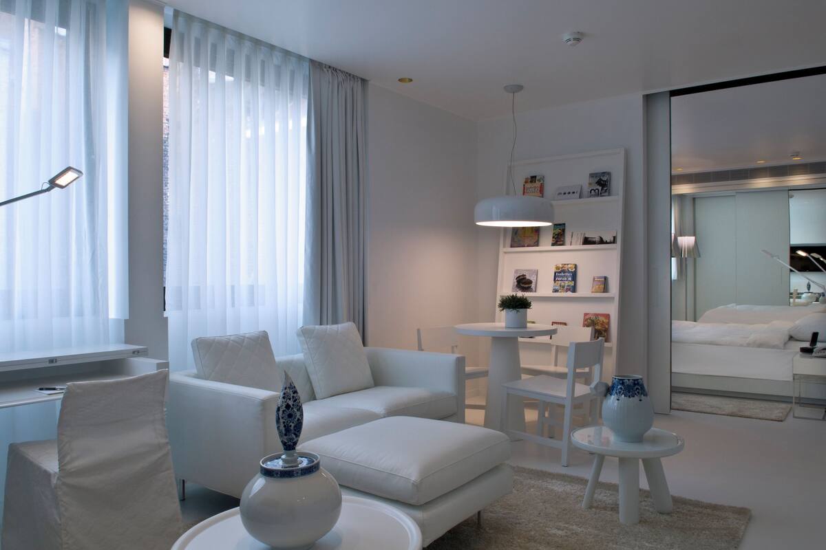Una sala de estar moderna con un sofá blanco, una mesa de centro y una mesita auxiliar con jarrones decorativos.