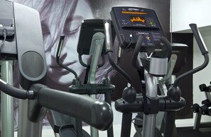 A stationary bike with a digital display and a wall-mounted screen in the background. - B-aparthotel Regent (Brussels)