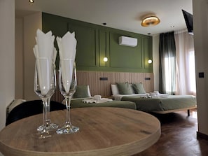 A hotel room with a bed, bedside tables, a round wooden table with two glasses, a wall-mounted air conditioner, and a ceiling light fixture. - Main Street Madrid (Madrid)