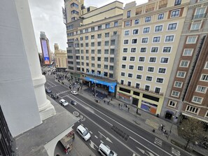 A multi-story building with a commercial ground floor, a pedestrian area, and a street with vehicles. - Main Street Madrid (Madrid)