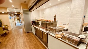 Una cocina moderna con piso de madera, electrodomésticos de acero inoxidable y una vitrina de vidrio con alimentos.