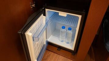 Een compacte koelkast met een houten afwerking, geplaatst in een hoek van een kamer met houten vloeren.