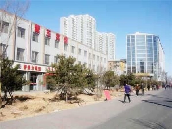 A street with buildings, including a multi-story residential building and a modern glass structure.