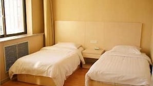 Ein Hotelzimmer mit zwei Einzelbetten, einem Fenster mit Vorhängen und einer Heizung.