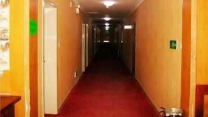Ein Hotelkorridor mit Holzwänden, einem roten Teppich und Türen an beiden Seiten.
