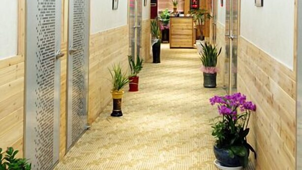 Un pasillo de hotel con paneles de madera, una recepción y plantas en macetas.