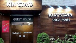 Entrada a una casa de huéspedes con un letrero que dice "KIM'STAY9 GUEST HOUSE" y un letrero que dice "Live Love Letter".