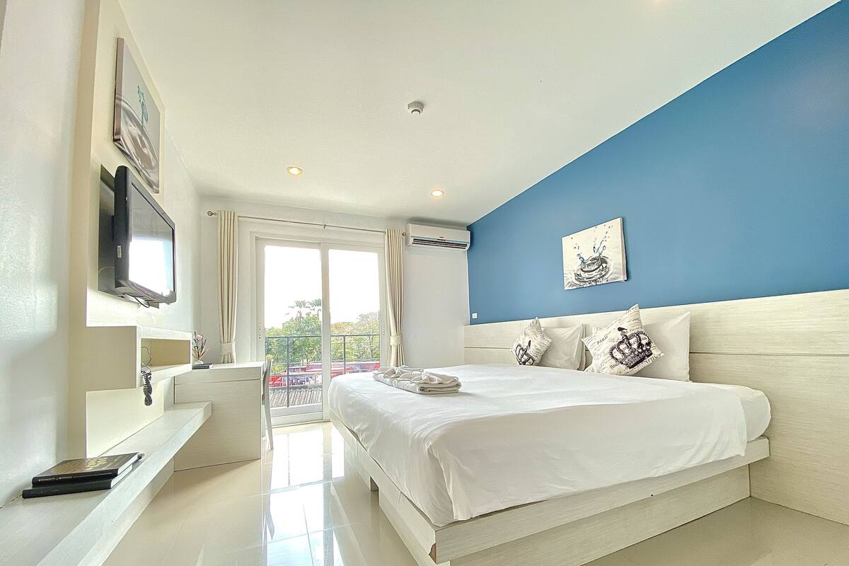 Ein modernes Schlafzimmer mit einem großen Bett, einem an der Wand montierten Fernseher und einem Balkon mit Blick.